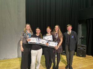 5 people smiling for a photo, with 2 students holding certificates