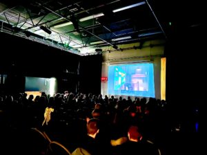 Students in a dark hall watching a movie projected on the wall